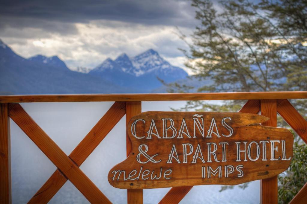 a sign on a fence with a view of the mountains at Melewe in Villa La Angostura