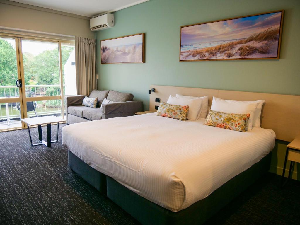 Habitación de hotel con cama grande y sofá en Nightcap at Hinterland Hotel Nerang, en Gold Coast