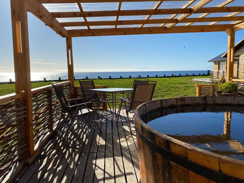 une terrasse avec un bain à remous, une table et des chaises dans l'établissement El Reflejo Lodge Spa - Queilen - Chiloé, à Queilén