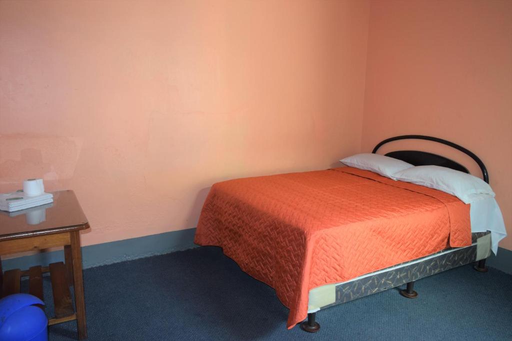 een kleine slaapkamer met een bed en een tafel bij Hotel Asunción in Guatemala