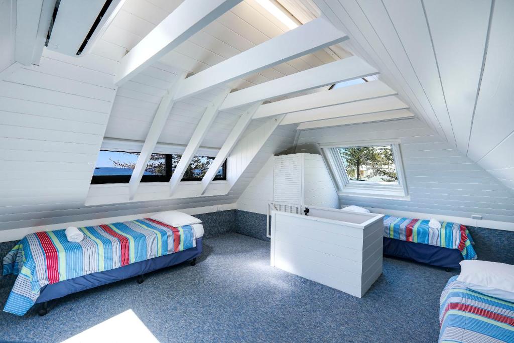 a attic bedroom with two beds and a desk at The Breakers in Gold Coast