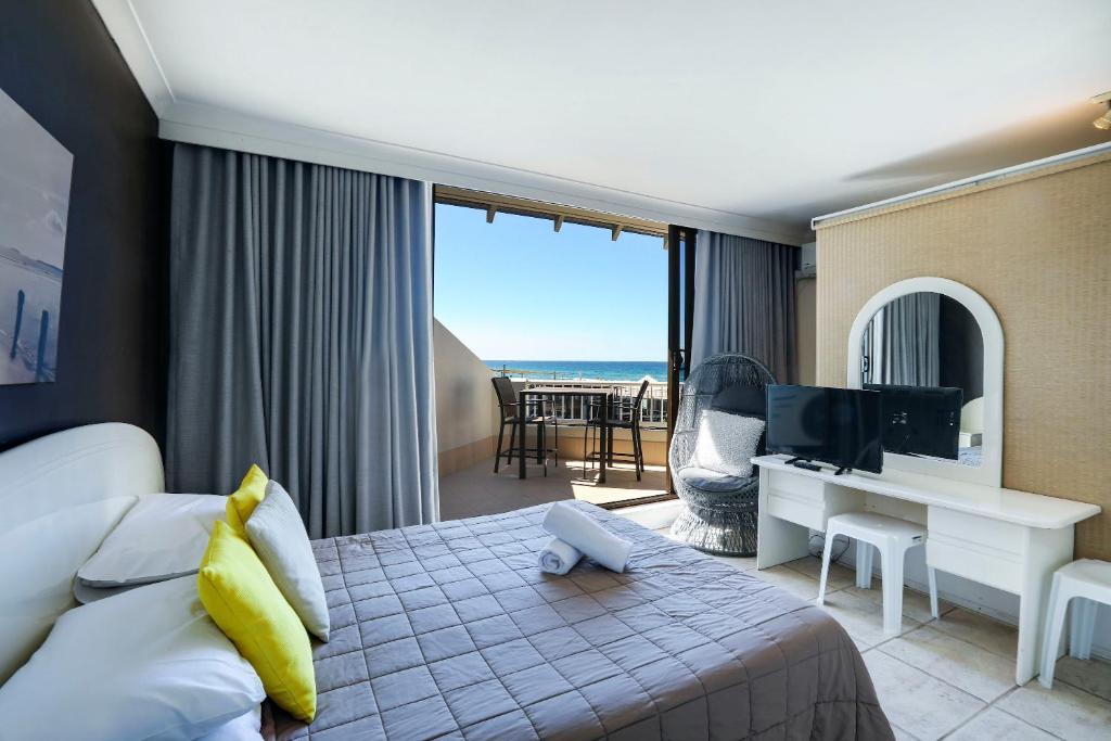 a hotel room with a bed and a desk and a television at The Breakers in Gold Coast