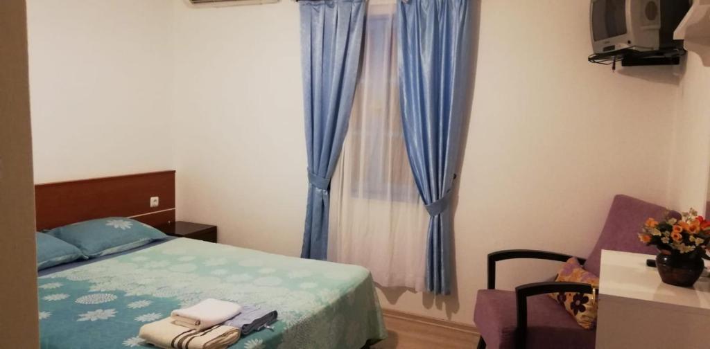 a bedroom with a bed and a window with blue curtains at Mavi Pansiyon in Bodrum City