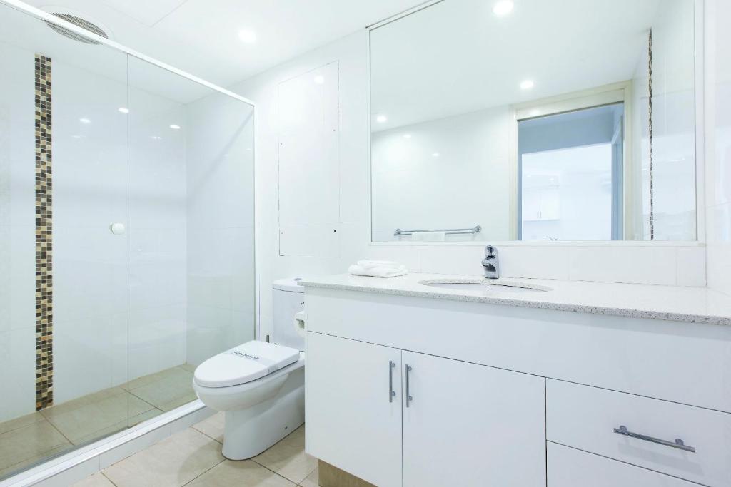a white bathroom with a toilet and a sink at The Breakers in Gold Coast