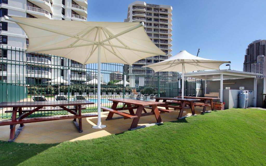 a row of picnic tables with umbrellas in the grass at The Breakers in Gold Coast