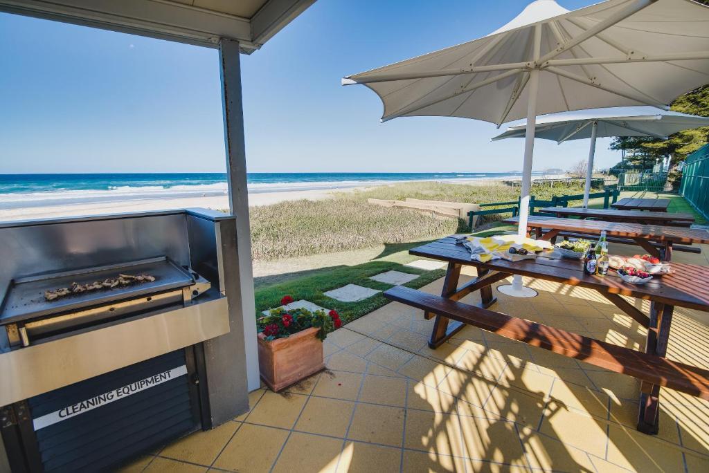 a patio with a grill and a table and an umbrella at The Breakers in Gold Coast