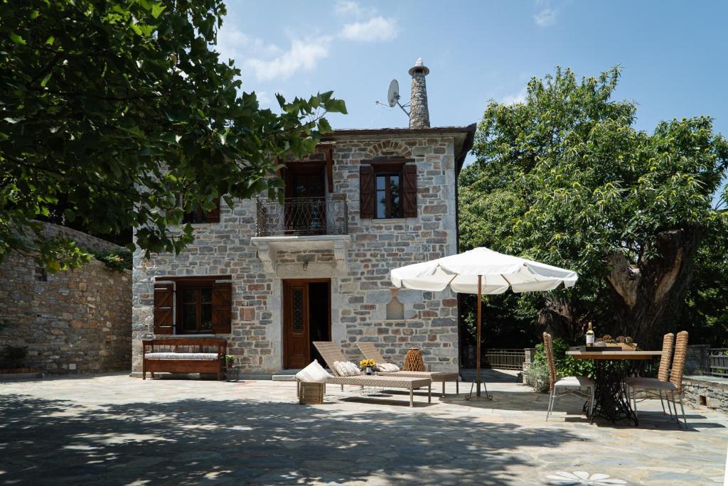 kamienny budynek z parasolem i stołem w obiekcie Helene Eco Luxury Villa w mieście Tsagarada