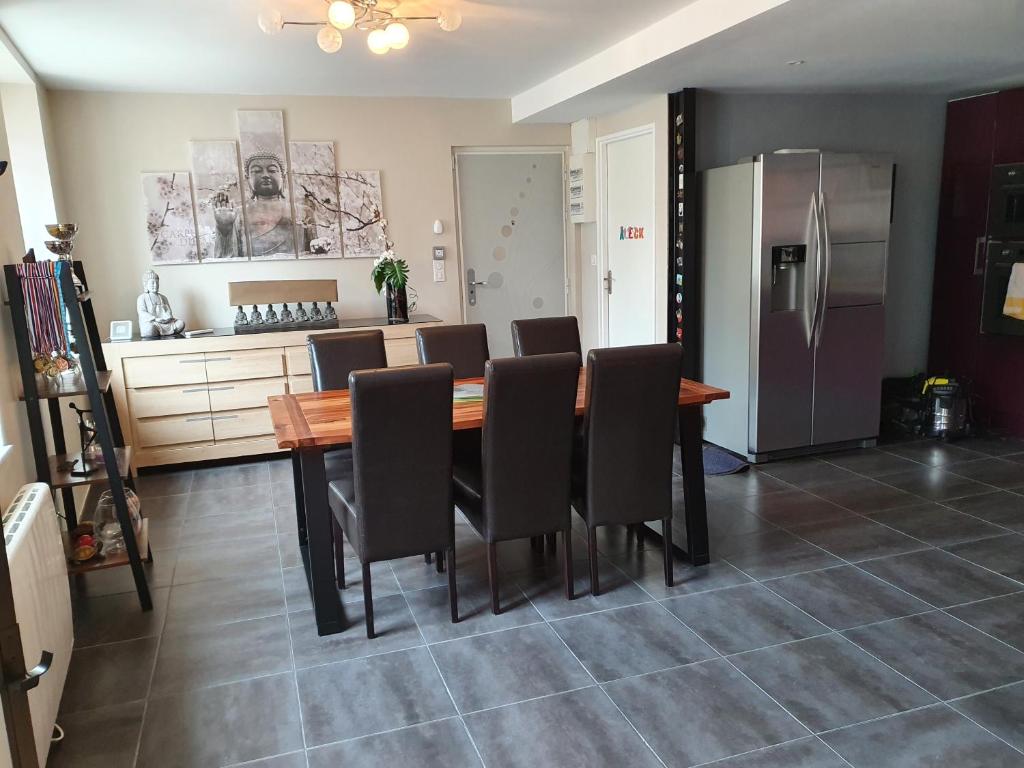 cocina con mesa, sillas y nevera en Appartement spacieux en Salins-les-Bains