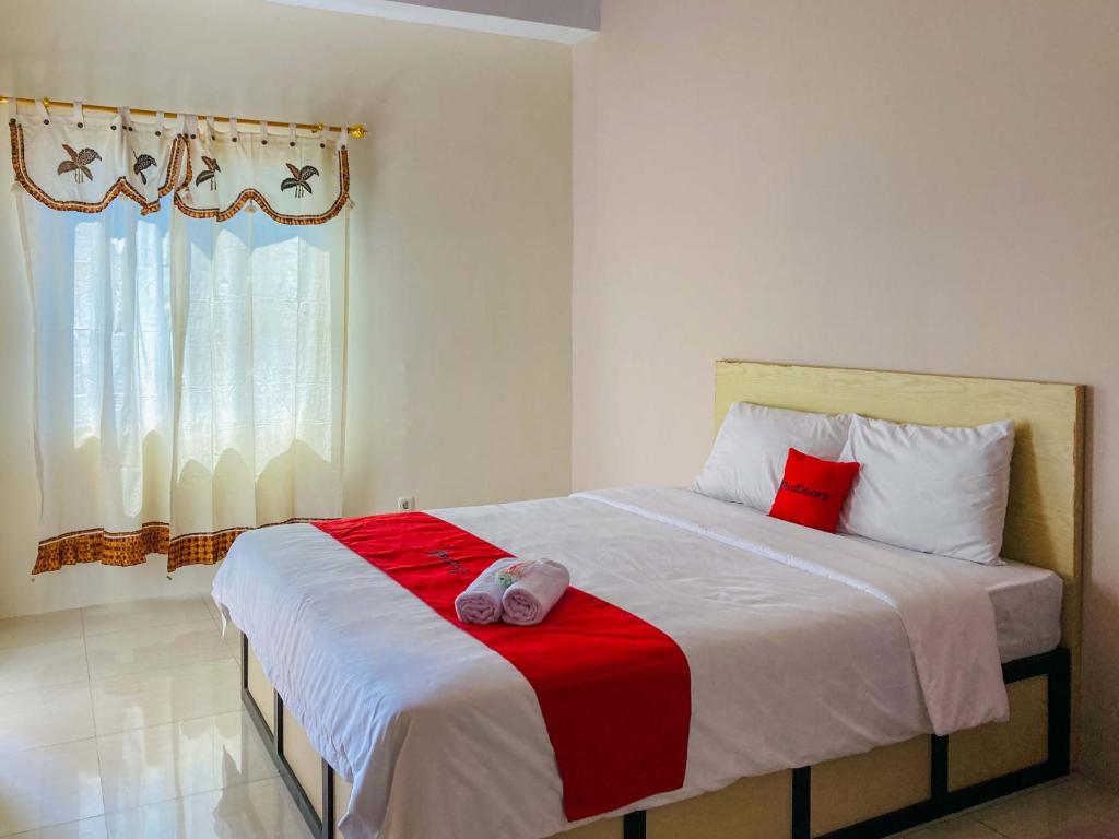 a bedroom with a bed with a red and white blanket at RedDoorz near Lippo Mall Yogyakarta in Demangan