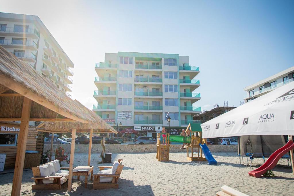einen Strand mit Stühlen, einen Spielplatz und ein Gebäude in der Unterkunft Ilinca Apart- Promenada Mamaia Nord in Mamaia Nord – Năvodari