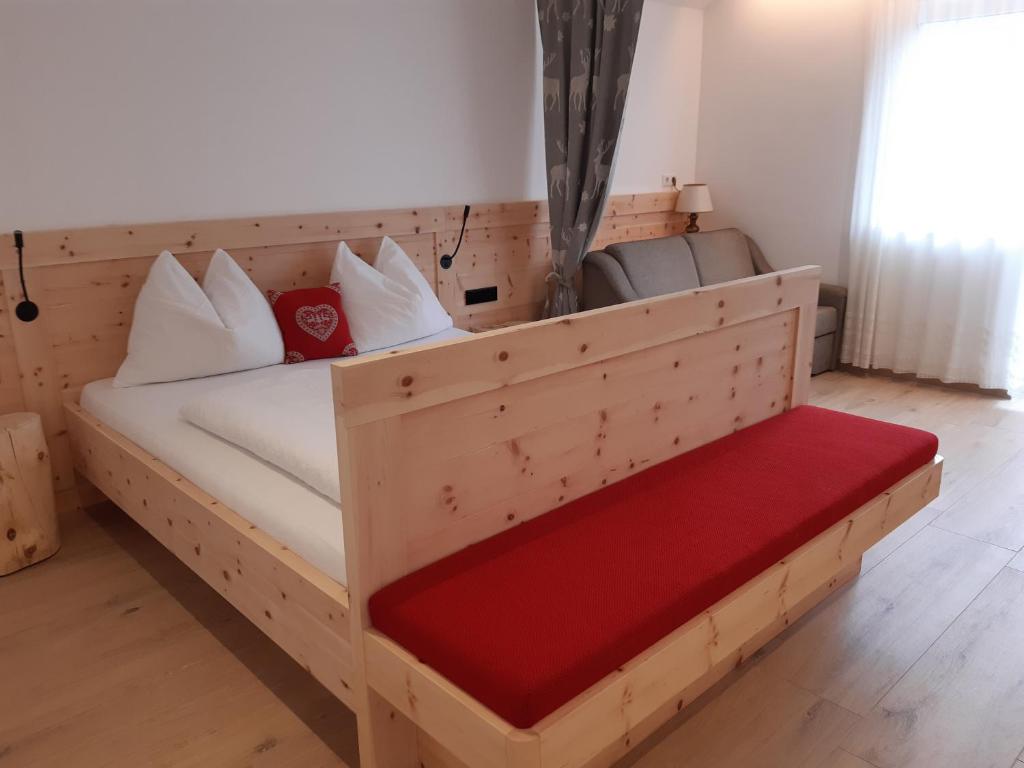 a wooden bed with a red bench in a room at Haus Talblick "Wallbug" Ferienwohnung 1 in Naturno