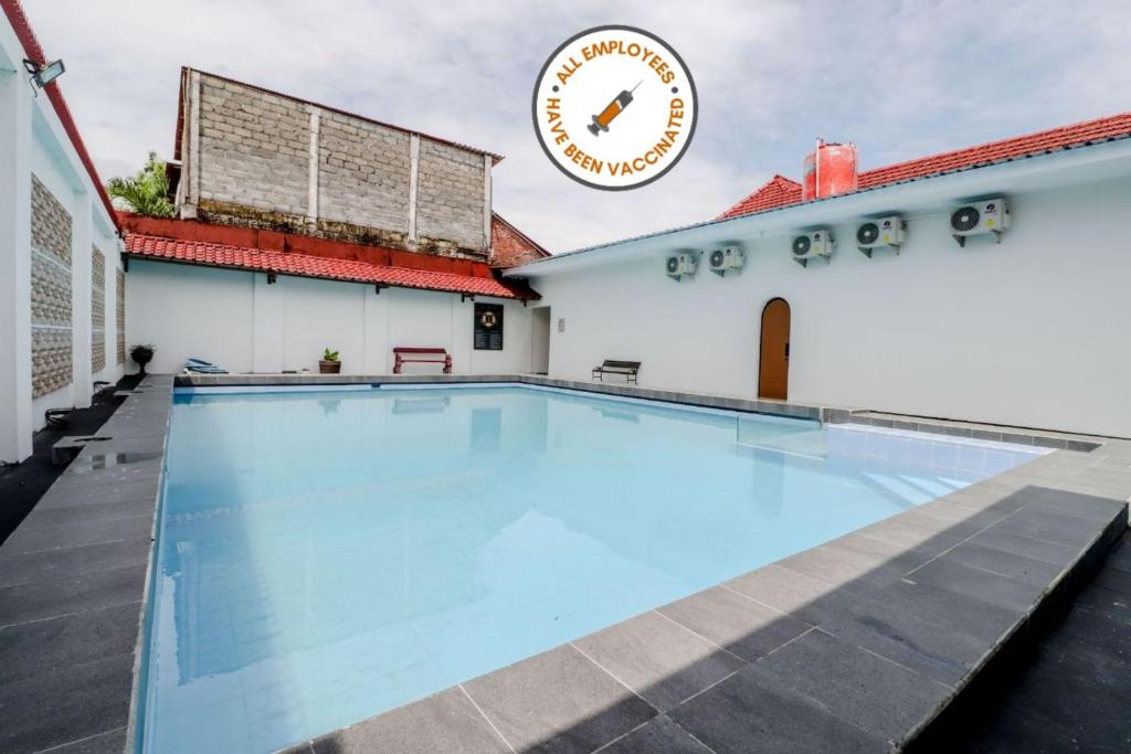 a swimming pool in front of a building with a clock at Hotel Sumaryo in Yogyakarta