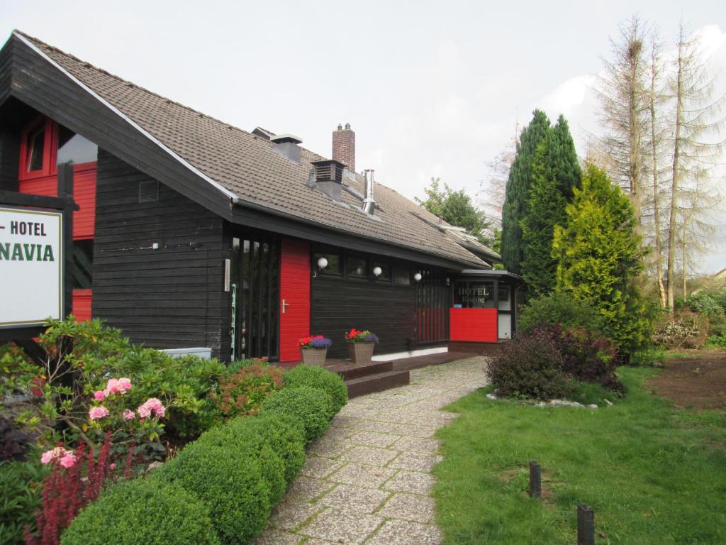 ein rotes und schwarzes Haus mit einem Schild davor in der Unterkunft Hotel Skandinavia in Sankt Andreasberg