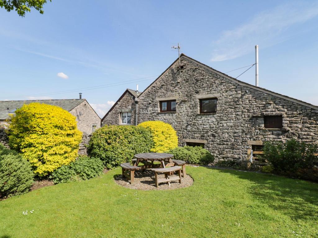 a picnic table in front of a stone building at Riven Oak in Kendal