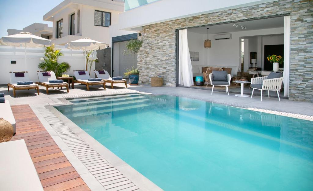 a swimming pool in a yard with chairs and a house at Chris Le Mare Gold Luxury Villa in Protaras