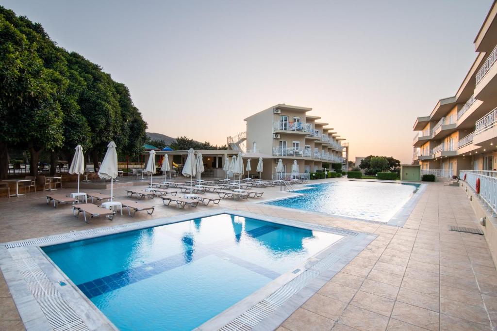 uma piscina com cadeiras e guarda-sóis num hotel em Chrissy's Paradise em Agia Pelagia