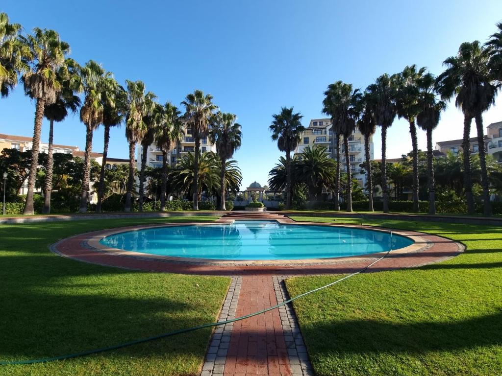 a swimming pool in a park with palm trees at Island Club by Smart City Stays in Cape Town
