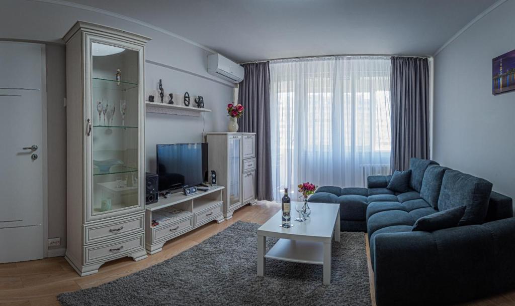 uma sala de estar com um sofá azul e uma televisão em Irene Central - Cozy house- 2 rooms em Bucareste