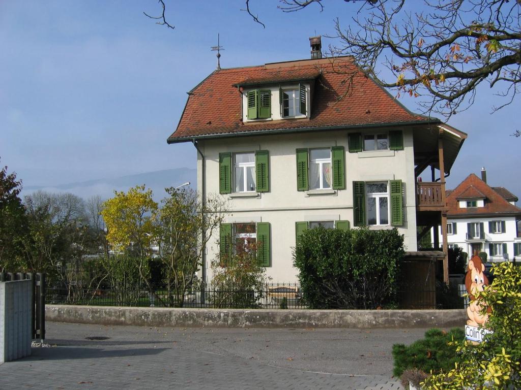 a white house with a red roof and green shutters at Zimmer Solothurn Doppelbett in Luterbach