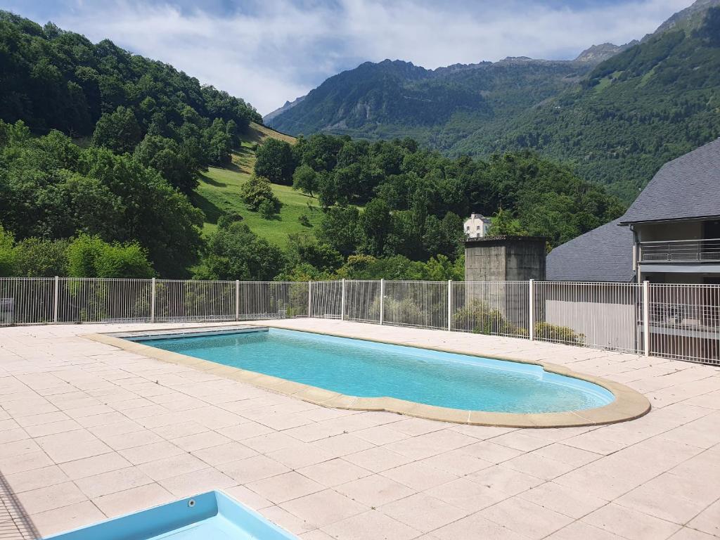 a swimming pool on a patio with mountains in the background at Appartement 6 places au cœur de Luz Saint sauveur in Luz-Saint-Sauveur