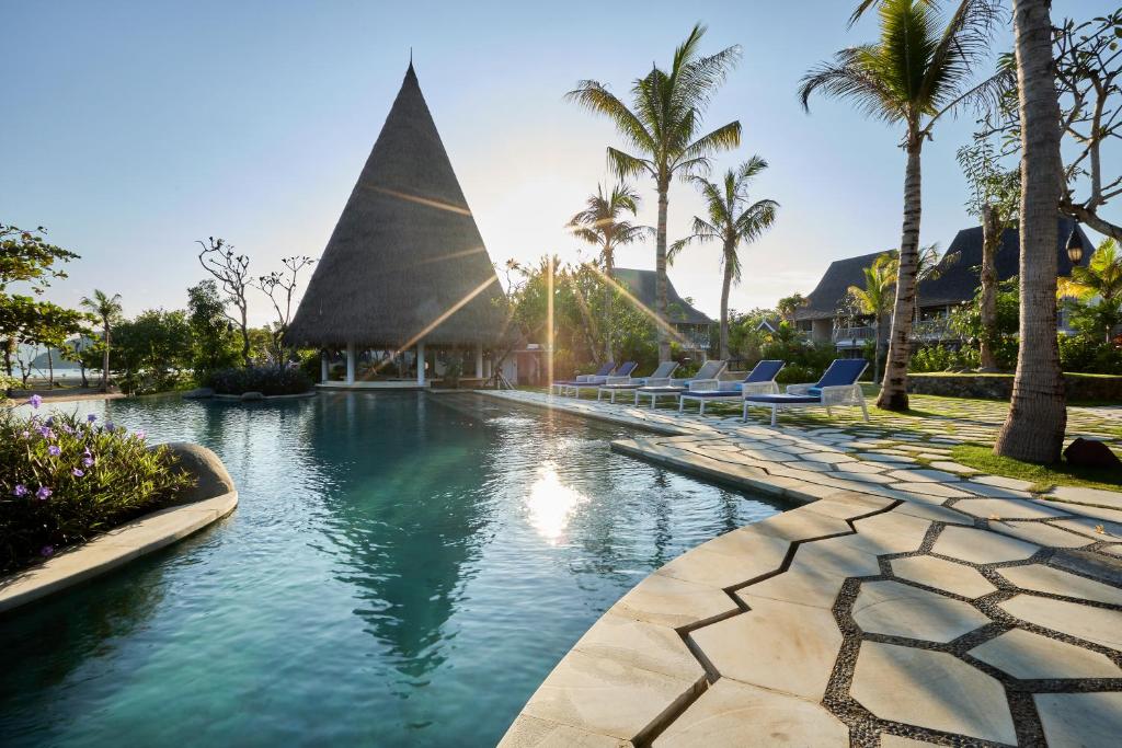 ラブハン・バジョにあるSudamala Resort, Komodo, Labuan Bajoのヤシの木とラウンジチェアのあるリゾートのプールを利用できます。