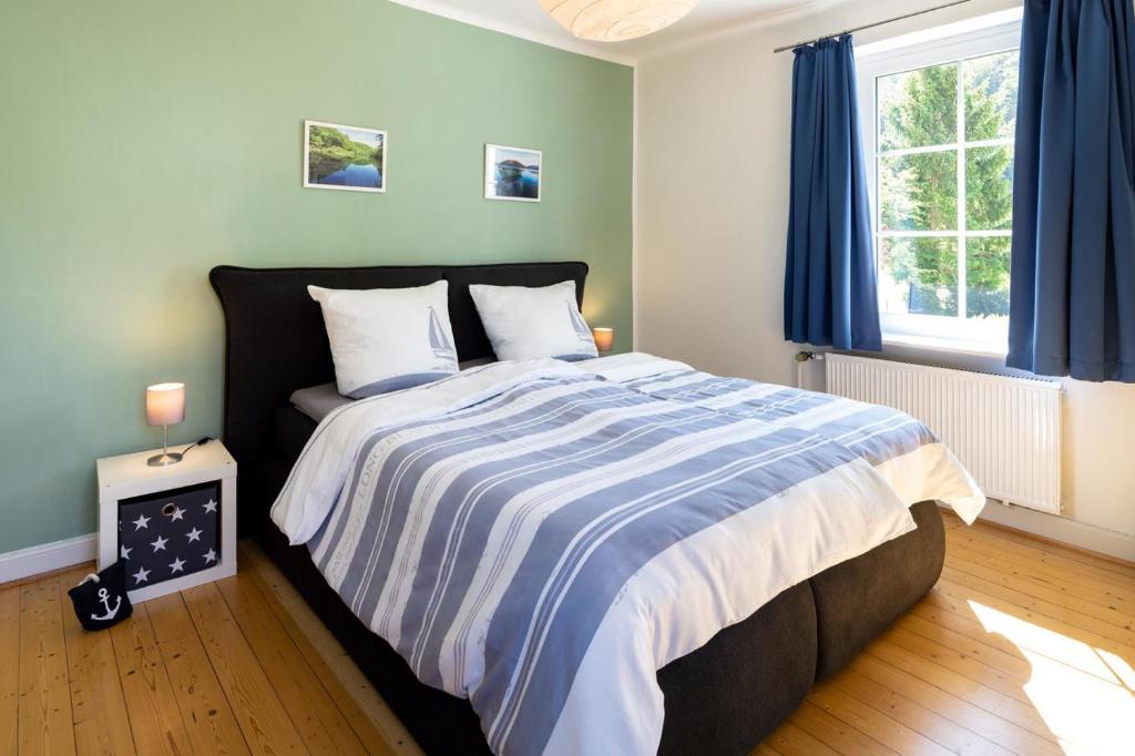 Schlafzimmer mit einem großen Bett und blauen Vorhängen in der Unterkunft Villa am Edersee in Hemfurth-Edersee
