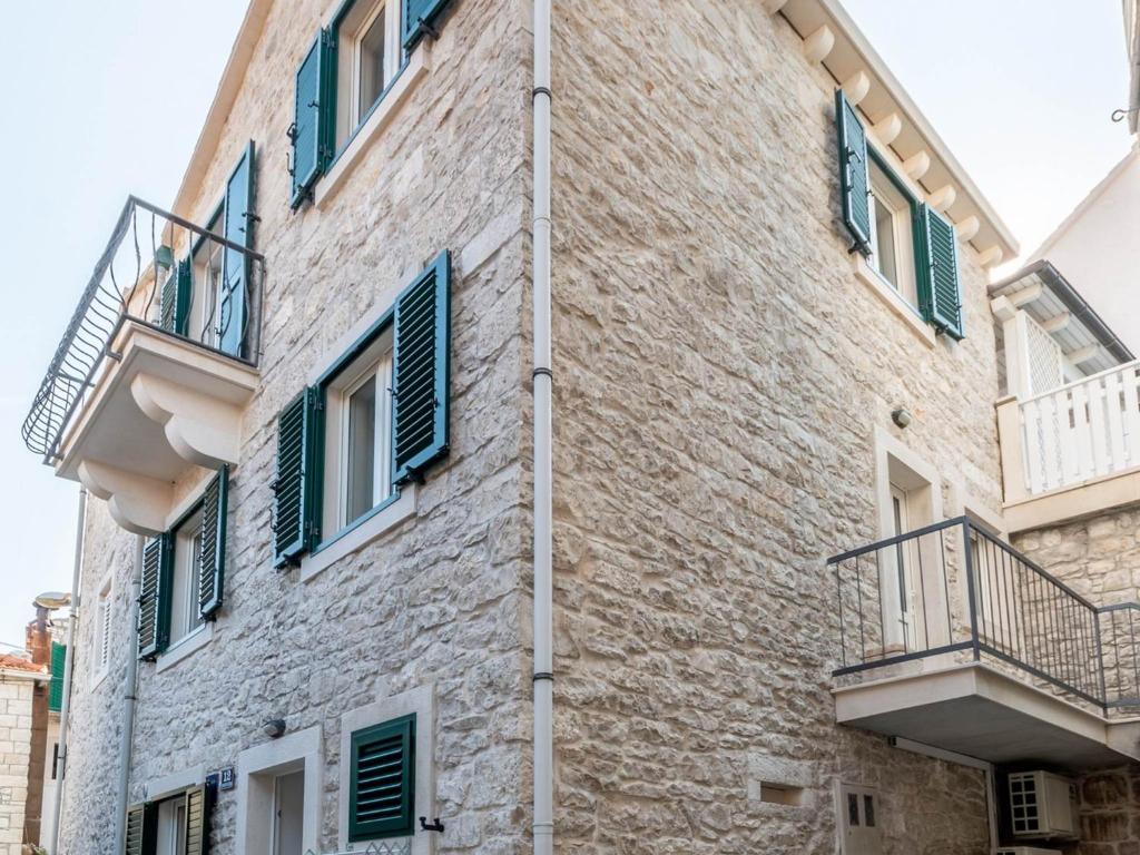 a brick building with green shutters on it at Apartments Sonja in Pučišća