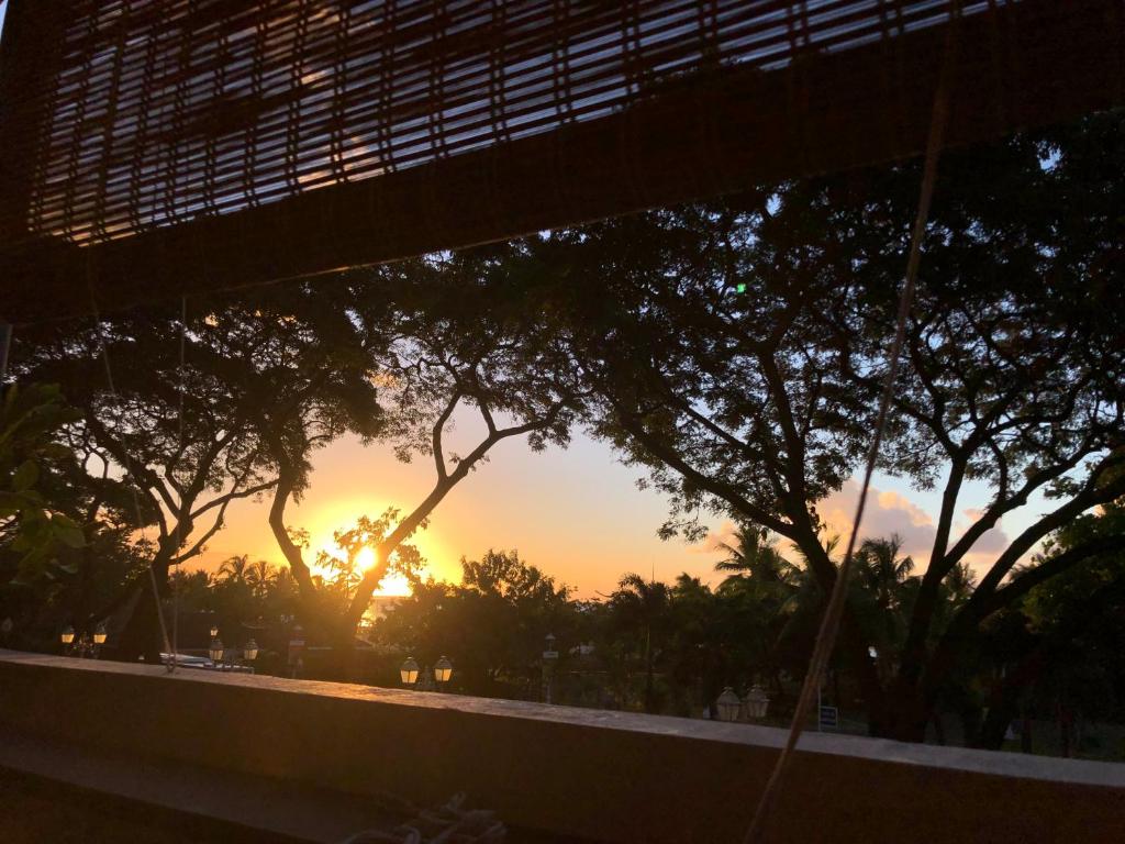 un coucher de soleil vu à travers la fenêtre d'un bâtiment avec des arbres dans l'établissement Pied à terre du front de mer, à Papeete