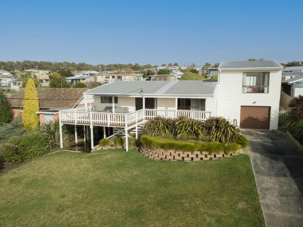 a white house with a porch and a yard at Dune Views in Bridport