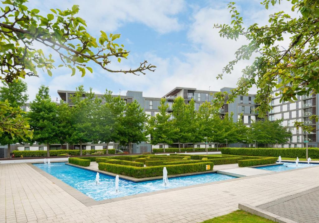 an image of a courtyard with trees and bushes at The Vizion serviced apartments from Pincott Properties - free parking, private balcony, and WiFi in Milton Keynes