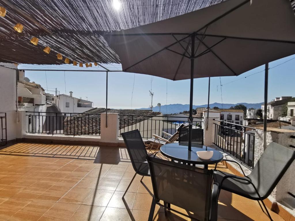 eine Terrasse mit einem Tisch, Stühlen und einem Sonnenschirm in der Unterkunft Casa de la Parra in Bédar