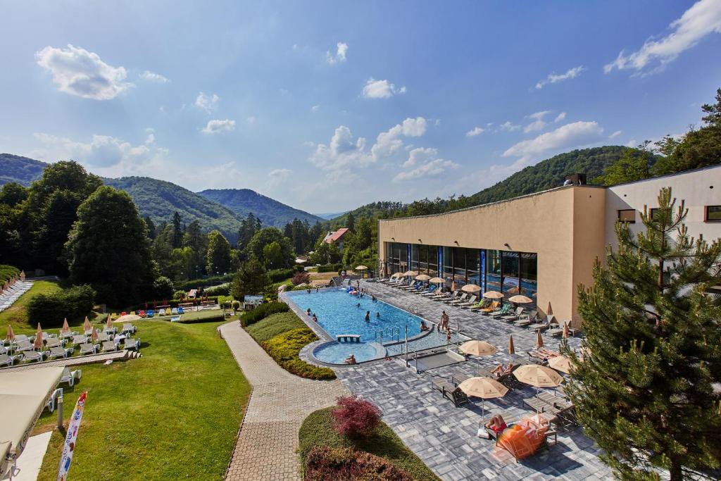 a resort with a large swimming pool and a building at Hotel Sitno Forest Resort in Vyhne