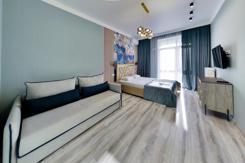 um quarto com um sofá, uma cama e uma televisão em Новая квартира люкс в центре ЖК "Атлант" em Astana