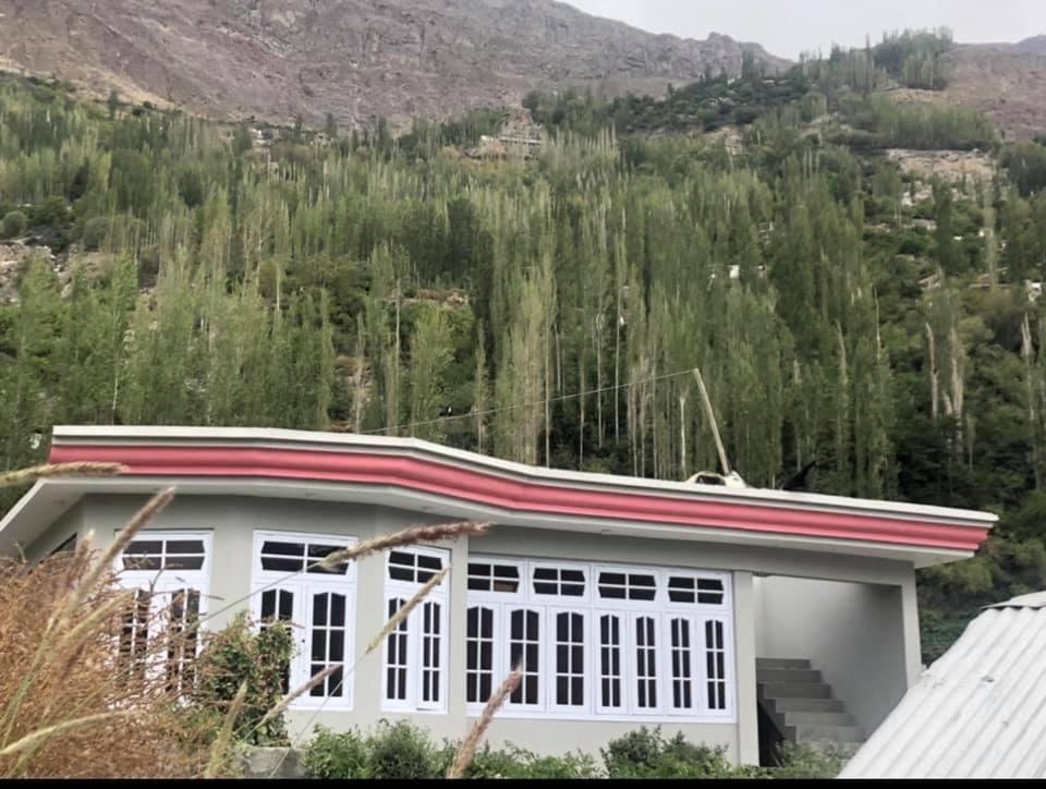 a white house with a mountain in the background at Green Guest House Altit Hunza in Hunza