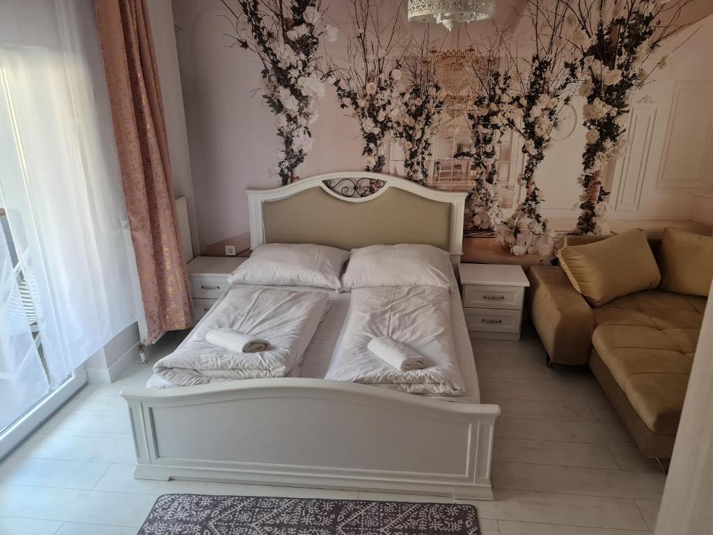 - un lit blanc dans une chambre avec un canapé dans l'établissement Borostyán Vendégház, à Egerszalók
