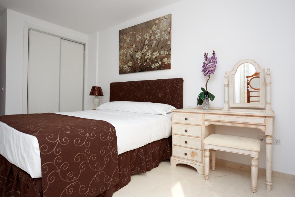 a bedroom with a bed and a dresser and a mirror at Apartamentos Anfiteatro in Benidorm