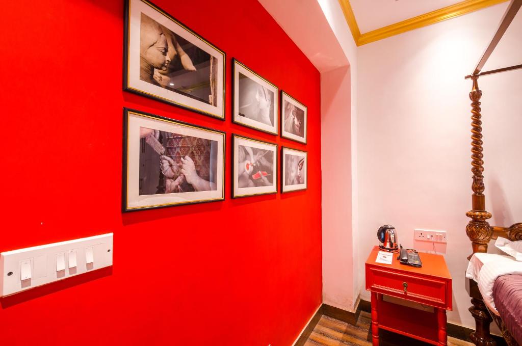 a red wall in a bedroom with pictures on it at The Corner Courtyard in Kolkata