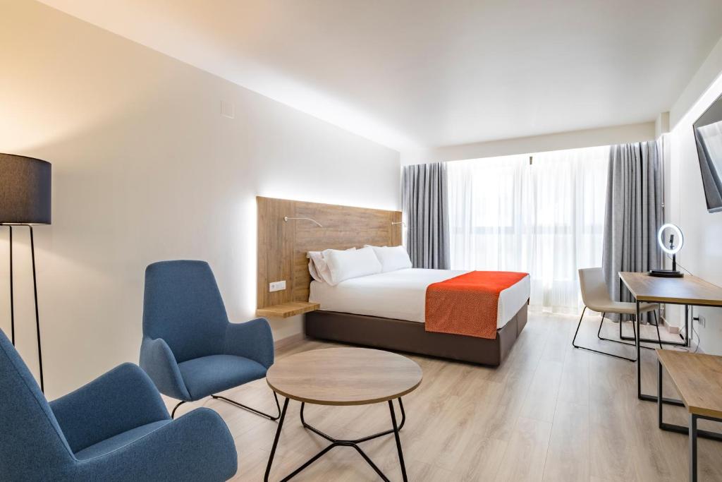 Habitación de hotel con cama, sillas y mesa en Exe Prisma en Andorra la Vella