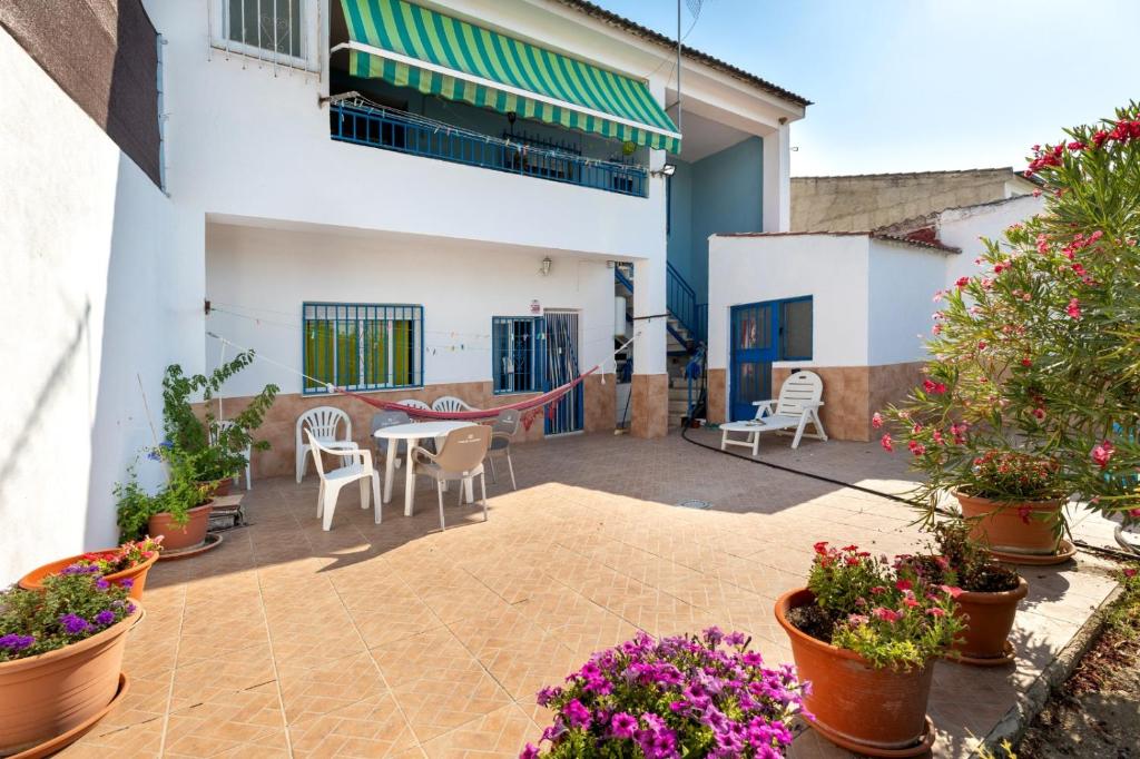 un patio con mesa, sillas y flores en Casa de Mar y Kanela 17 km Granada, en Fuente Vaqueros