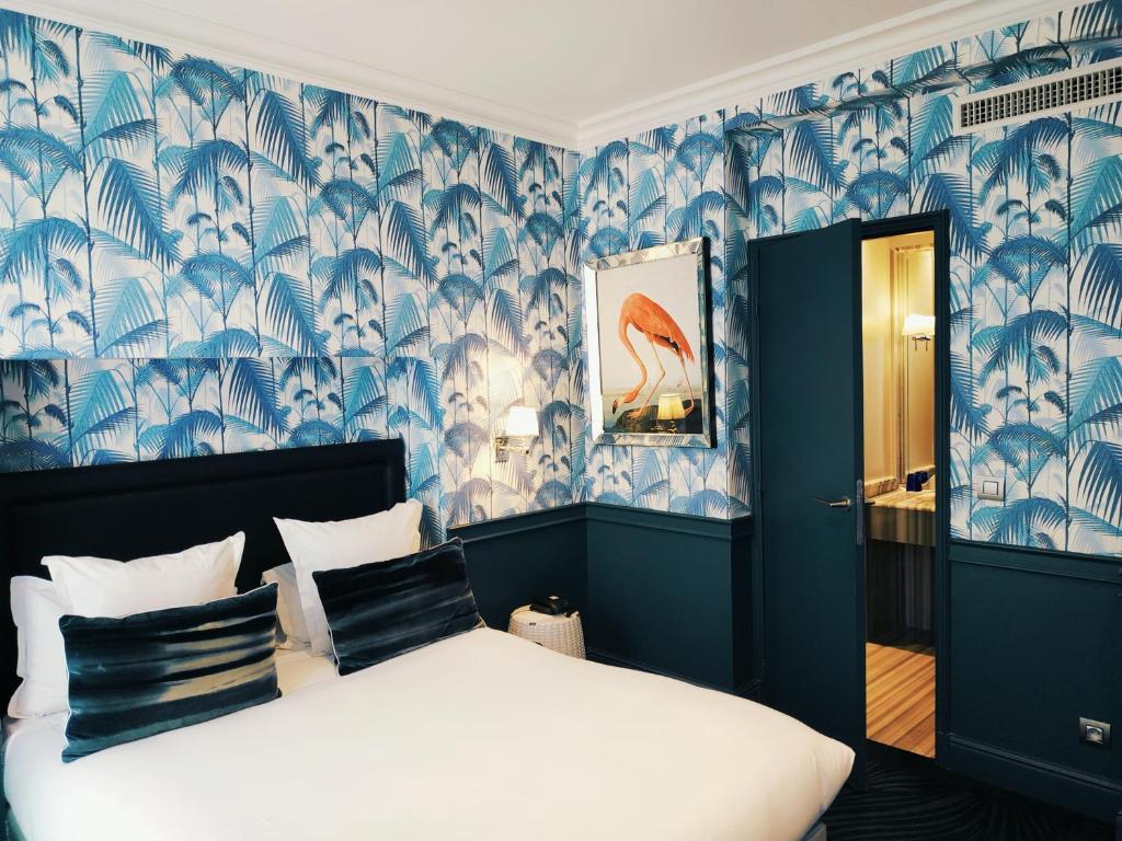 ein Schlafzimmer mit einem Bett mit blauen und weißen Tapeten in der Unterkunft Hôtel George Washington in Paris