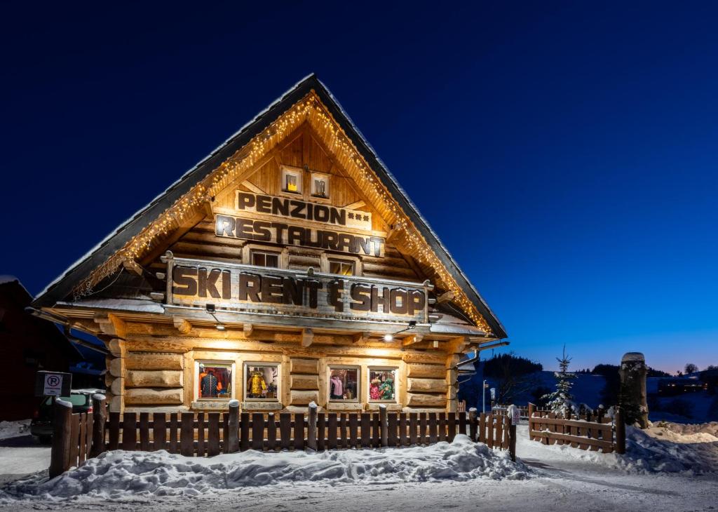 a log cabin in the snow at night at Penzion Damisport in Donovaly