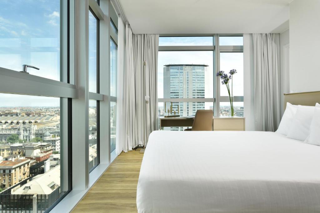 sypialnia z dużym łóżkiem i dużymi oknami w obiekcie Torre Galfa Milano Luxury Apartments | UNA Esperienze w Mediolanie