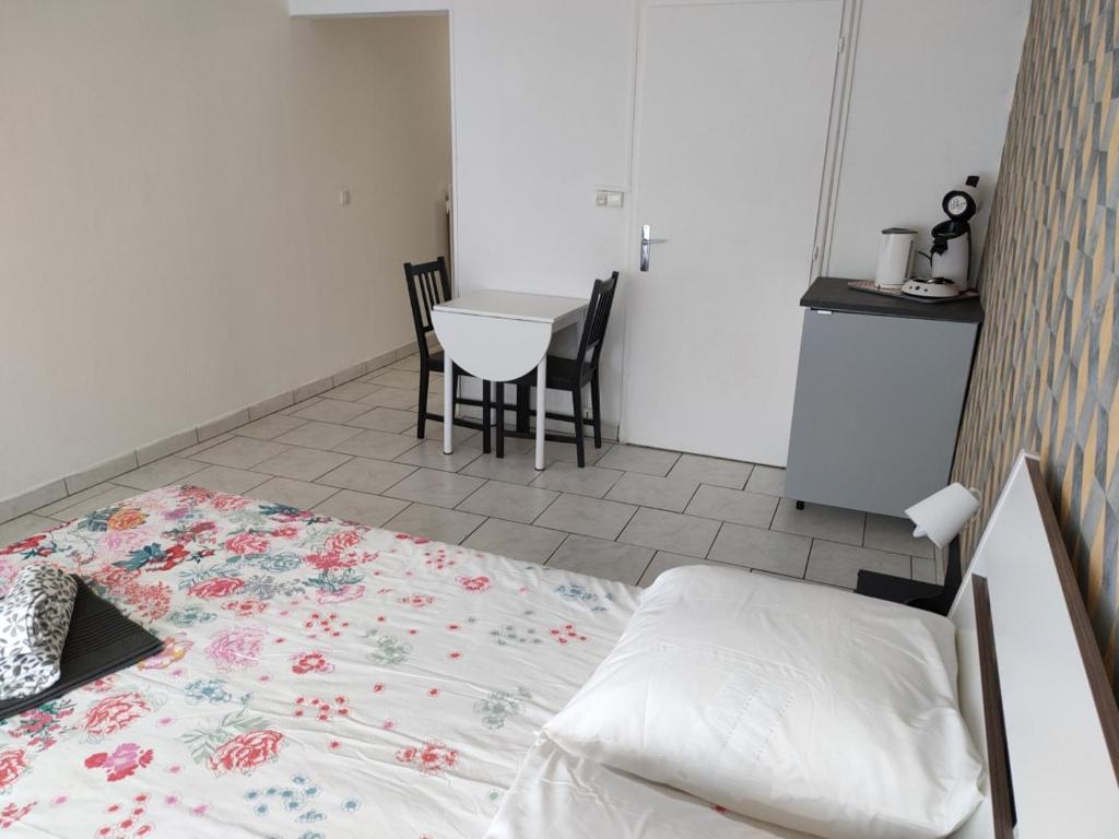 een slaapkamer met een bed en een tafel met stoelen bij Studio Galy in Metz