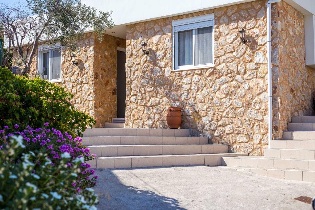 a stone house with stairs and a window and flowers at Errik Luxury House in Faliraki