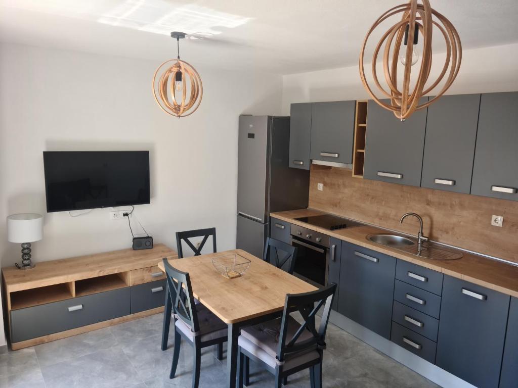 a kitchen with blue cabinets and a wooden table with chairs at Hello Sunshine - Apartment on the Beach in Zubovići