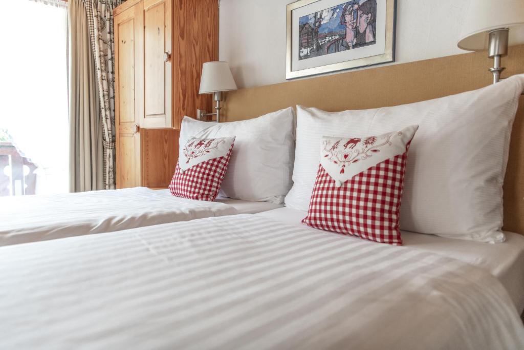a bed with two red and white pillows on it at Hotel Steinbock in Klosters