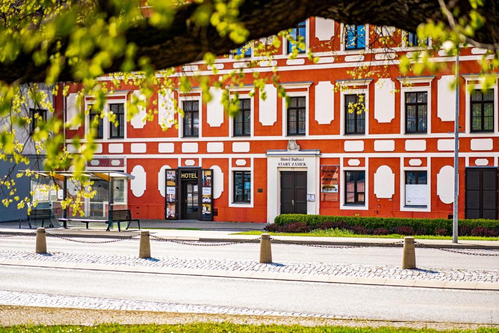 een rood-wit gebouw met een bank ervoor bij Hotel Baltaci Starý Zámek in Napajedla