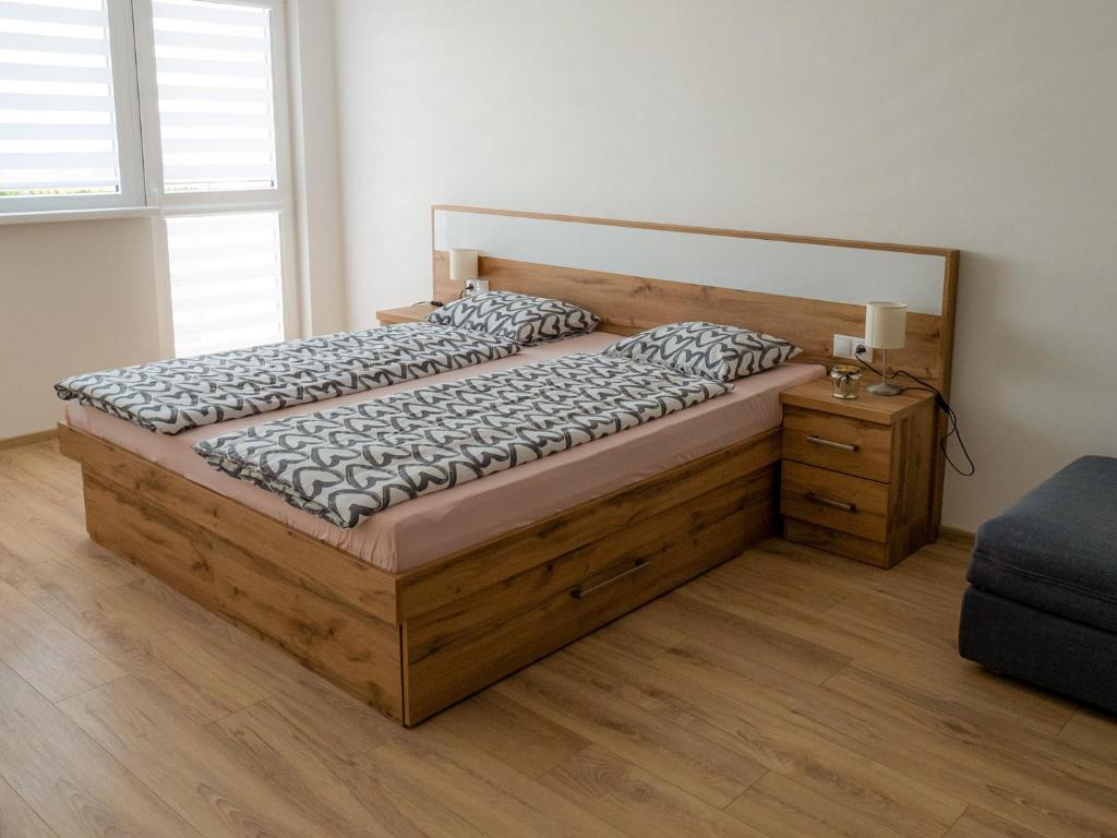 a bedroom with a large wooden bed with a night stand at Apartmany Motocentrum in Kaluža