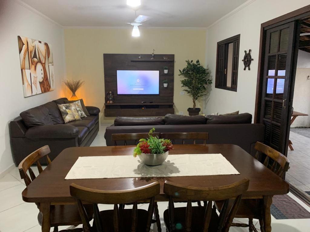 a living room with a table and a tv at Casa de Temporada Praia Juquehy in Juquei