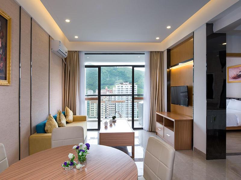 恵州市にあるVienna International Hotel Huizhou Daya Bay Century Cityのテーブルとリビングルームが備わるホテルルームです。